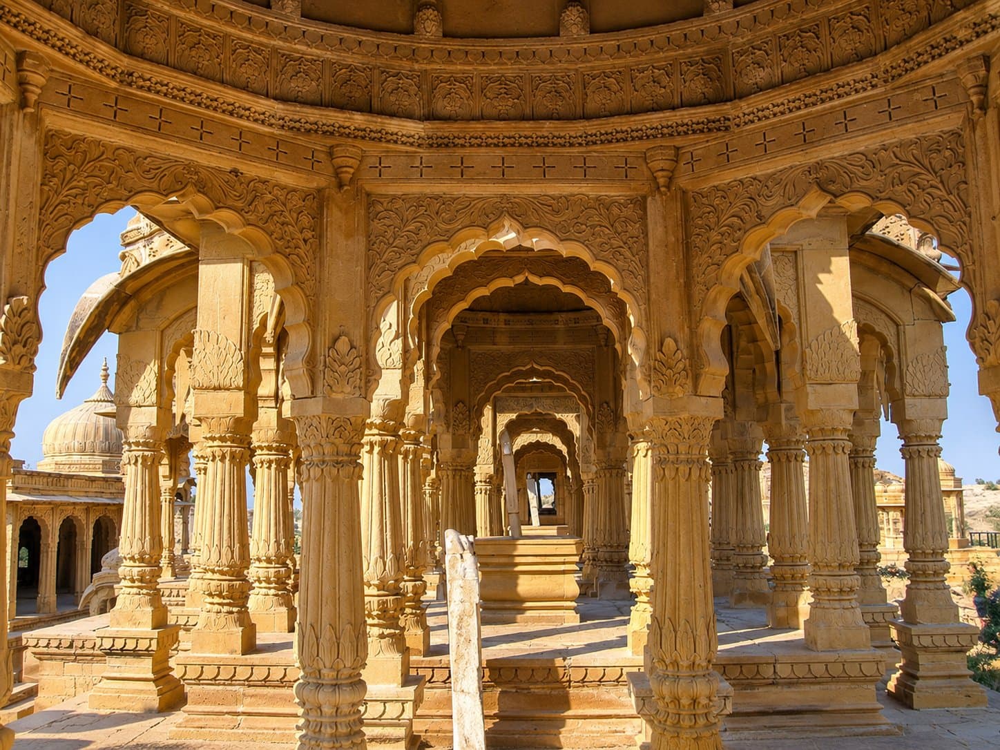 Carved golden-sandstone pillars and scalloped arches inside a royal chhatri at Bada Bagh, near Jaisalmer
