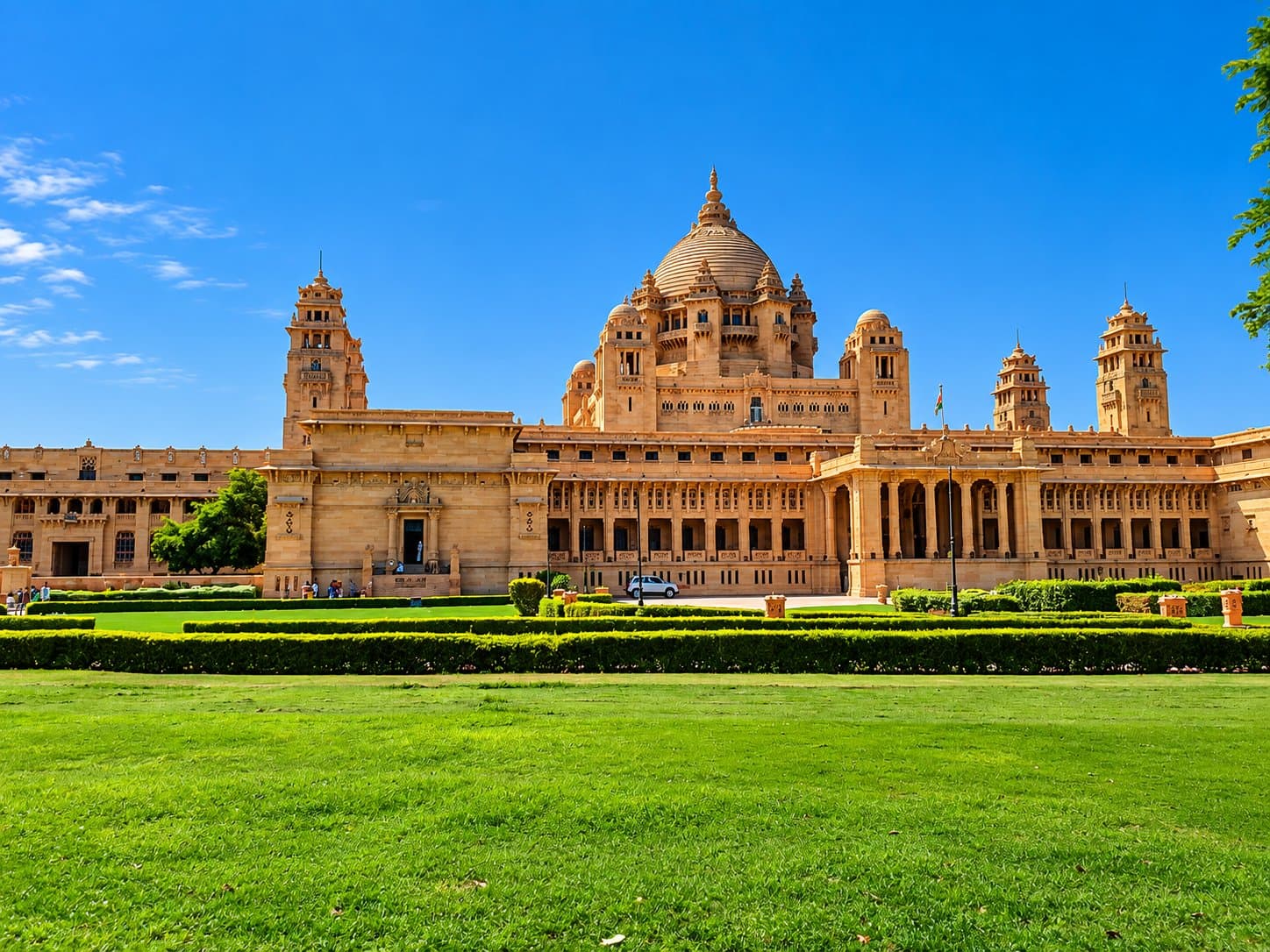 Umaid Bhawan Palace in Jodhpur: its sandstone dome and towers above a long facade, with a wide green lawn in front